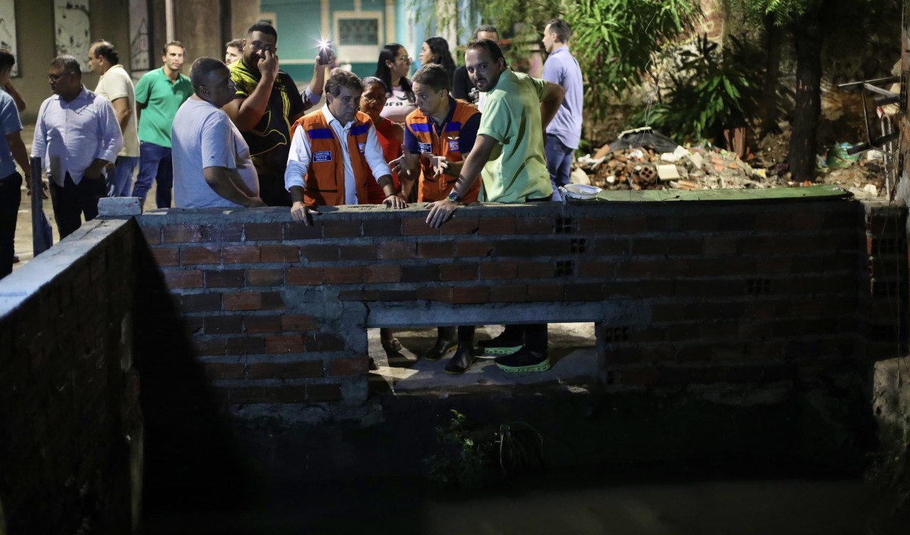 prefeito evandro conversa com a equipe da defesa civil à margem de um canal